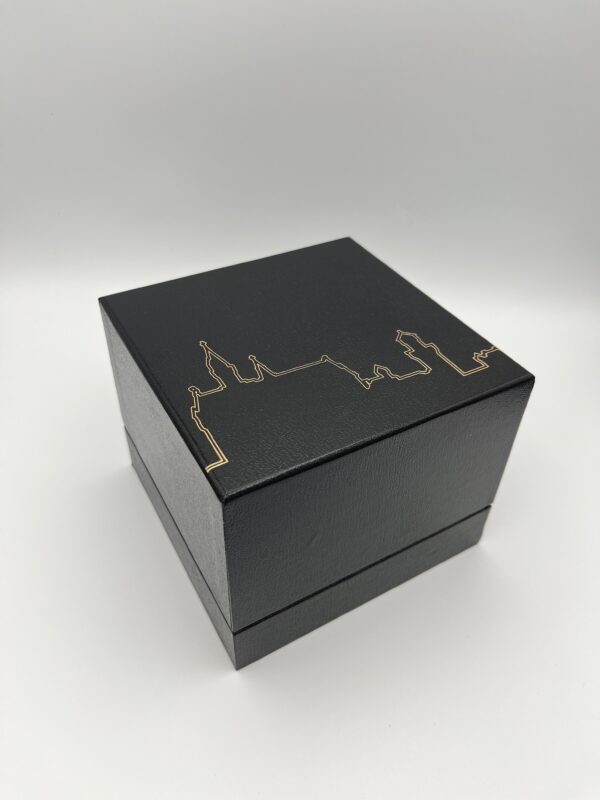 Schwarze Box in Würfelform. In goldener Farbe ist die Silhouette des Schloss Neuschwanstein auf dem Deckel zusehen.
