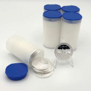 1 Bayern Thaler in Silber mit Motiv Neuschwanstein, daneben fünf Plastik Tube mit blauem Deckel gefüllt mit Bayern Thalern. Vor weißem Hintergrund.