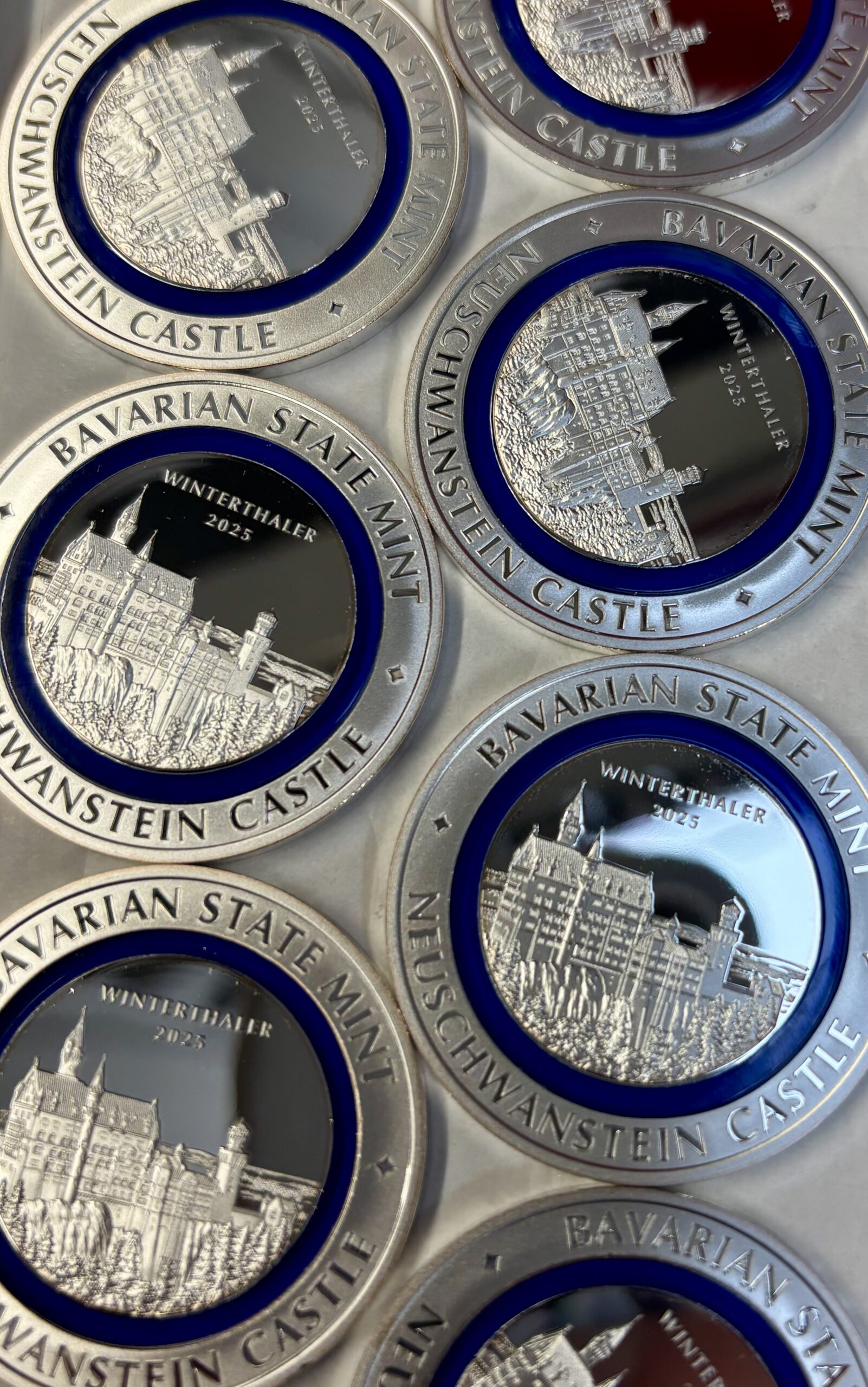 Mehrere Winter Thaler aus Silber mit blauem Polymerring liegen nebeneinander